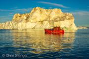 Iceberg and fishing vessel in midnightsun